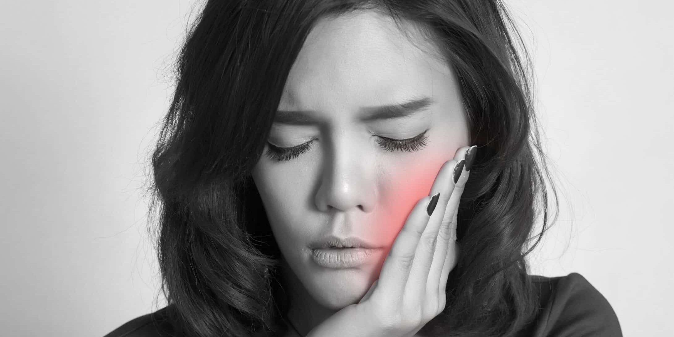 Teen woman pressing her bruised cheek with a painful expression as if she's having a terrible tooth ache.